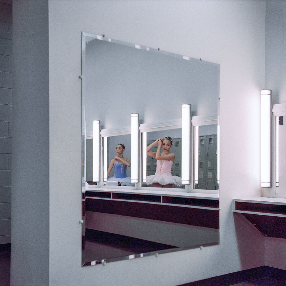 ballerina in mirror in the dressing room backstage fixes her hair.