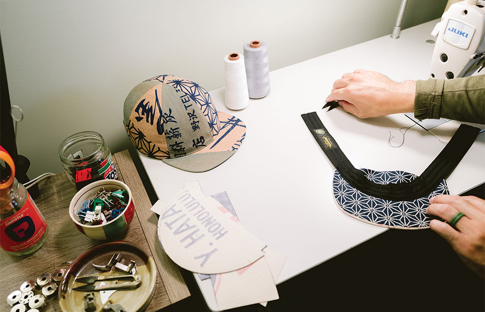 A hand sewing a hat on a table.